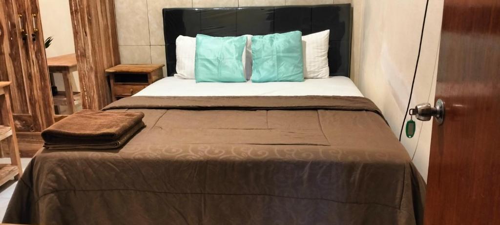 Una cama con dos almohadas azules encima. en Rumah Sedana, en Ubud