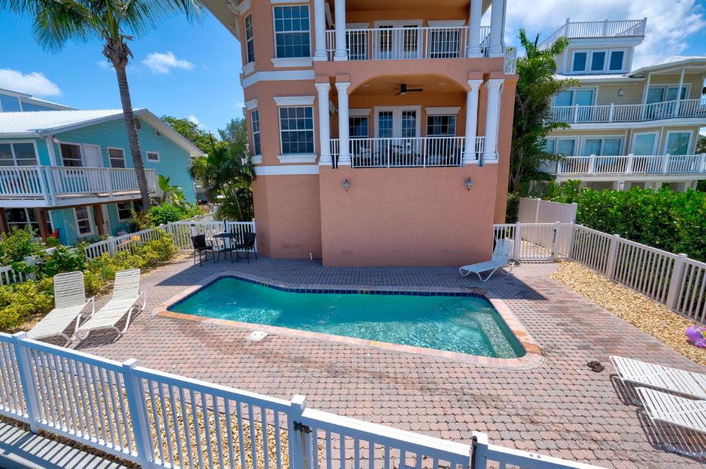a villa with a swimming pool in front of a house at Hibiscus Hideaway Condo Walk To Historic Bridge St in Bradenton Beach
