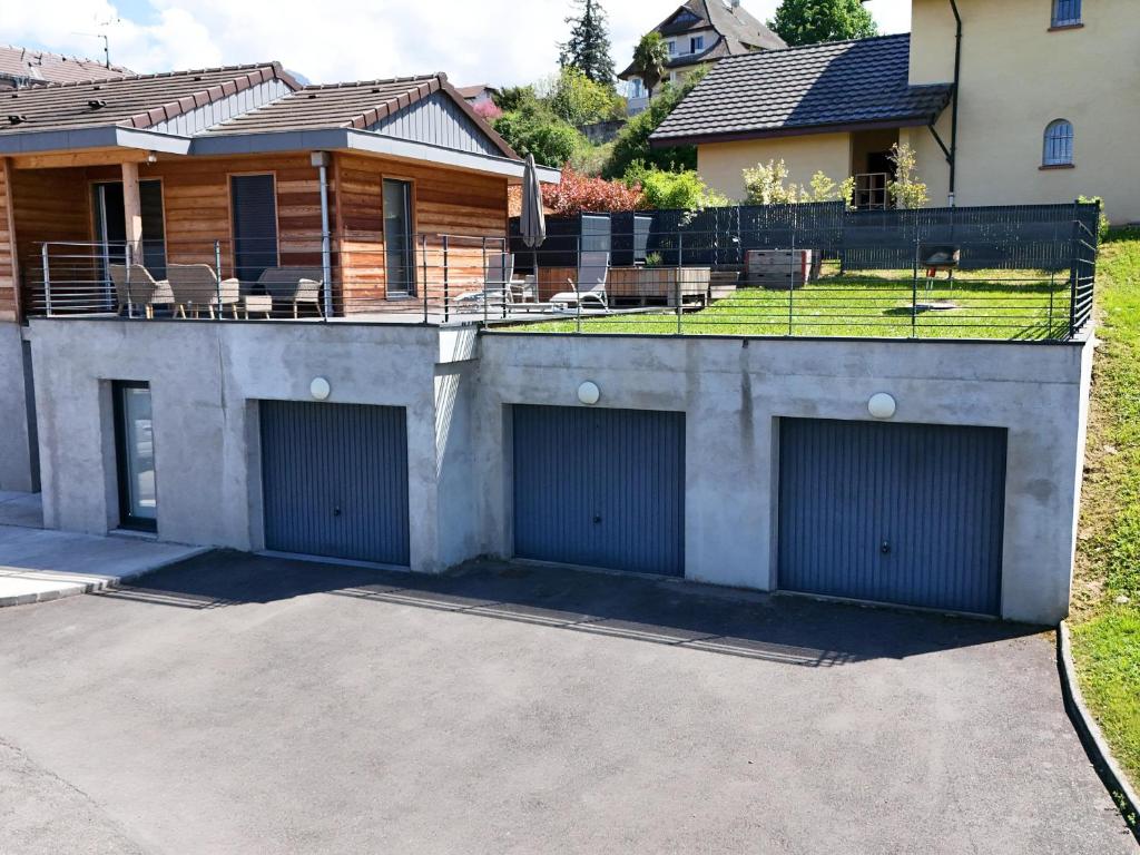 une maison avec deux portes de garage dans une allée dans l'établissement Charmante maison à Évian avec terrasse et parking - FR-1-498-113, à Évian-les-Bains