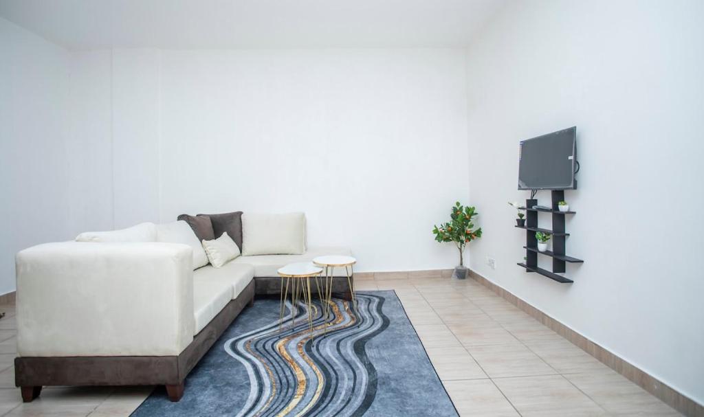 a living room with a white couch and a tv at Appartement Moderne & Confortable Proche Aéroport Léon-Mba, Libreville in Libreville