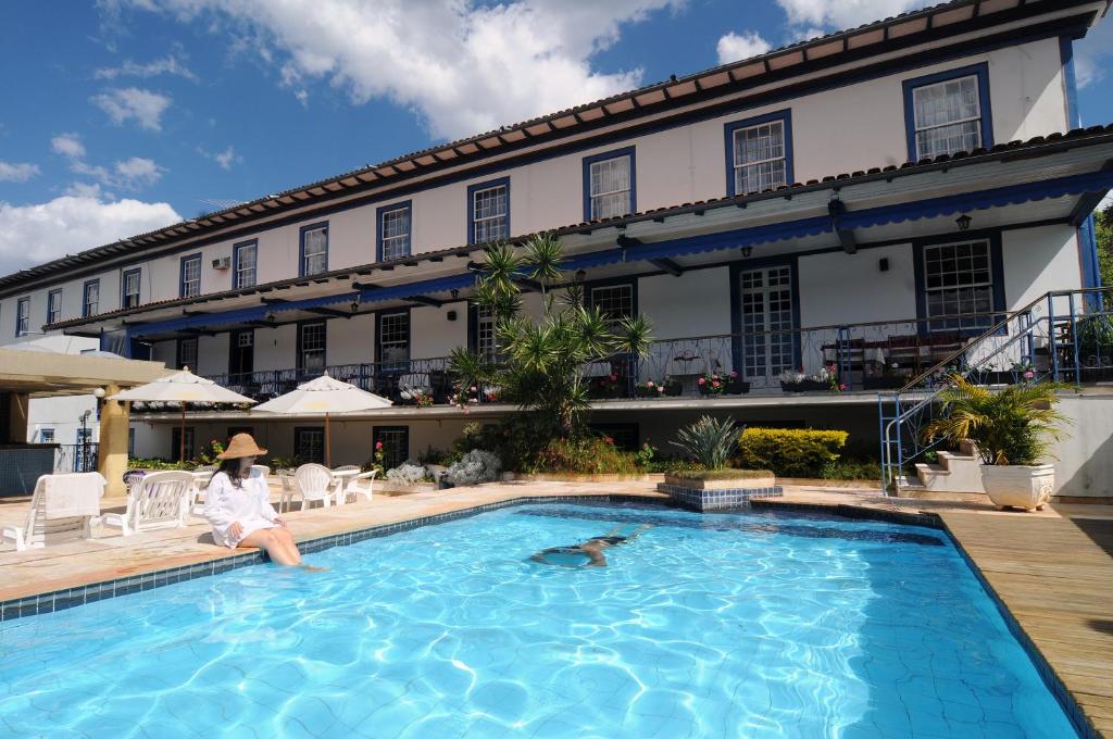 uma mulher sentada em frente a um hotel com uma piscina em Pousada do Garimpo em Diamantina