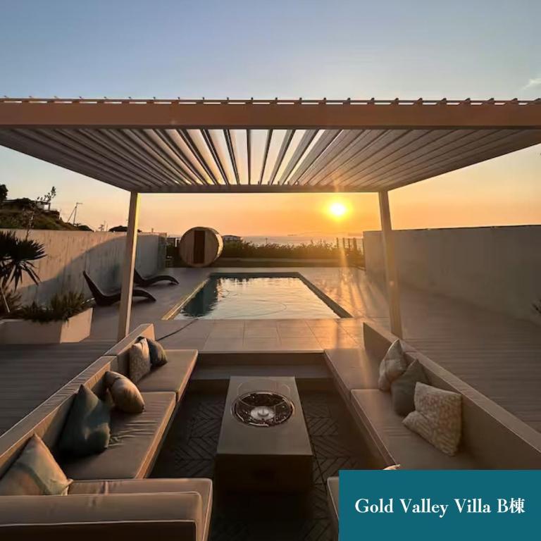 a patio with a couch and a pool with the sunset at Gold Valley Villa B in Futtsu