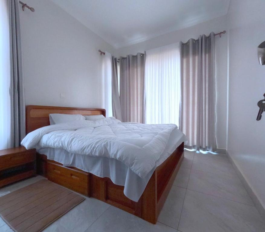 a bedroom with a large bed with white sheets at Cozy Home-Rusororo-near airport in Kigali