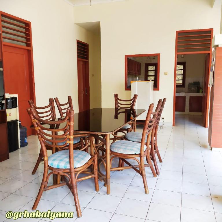 科贾扬Grha Kalyana Homestay的一间用餐室,配有一张黑桌子和木椅