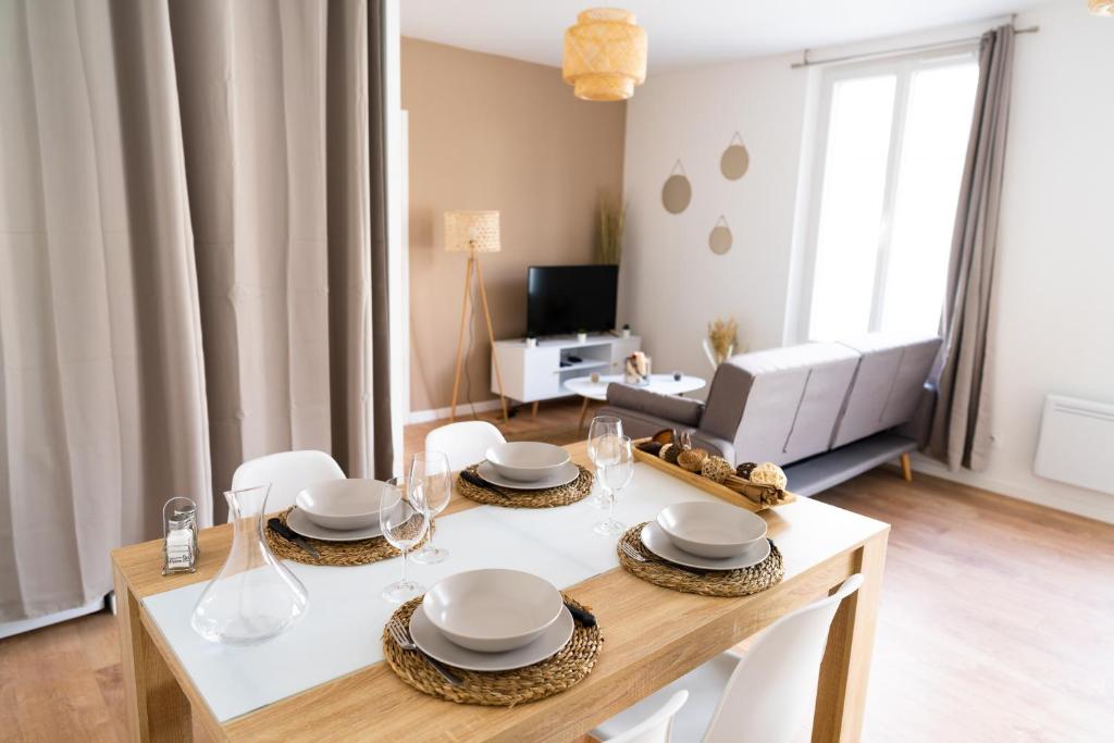 a dining room with a table and chairs and a living room at Spacieux appartement avec parking privé à Saumur in Saumur