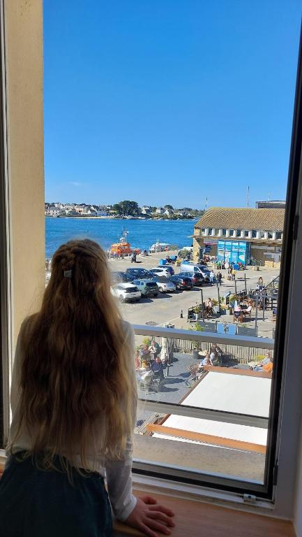 une fille regardant par la fenêtre sur une plage dans l'établissement Ty Kosy 2 ch vue imprenable Ria Etel, à Étel