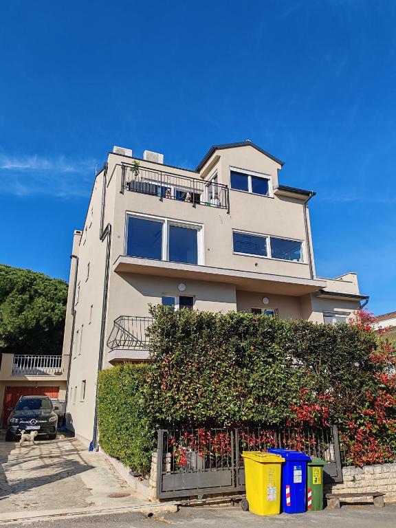 a large white building with a hedge in front of it at Apartments Mirta in Rovinj
