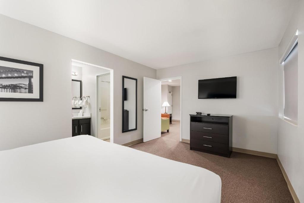 a white bedroom with a bed and a flat screen tv at MainStay Suites Chattanooga Hamilton Place in Chattanooga