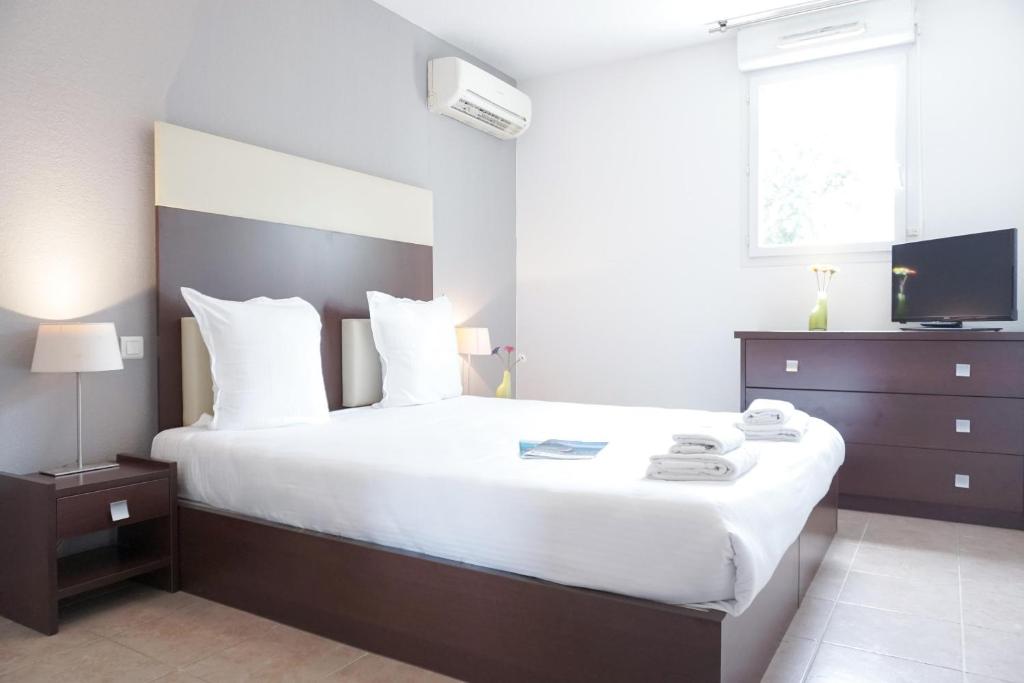 a bedroom with a large white bed and a television at Comfort Aparthotel Six-Fours in Six-Fours-les-Plages