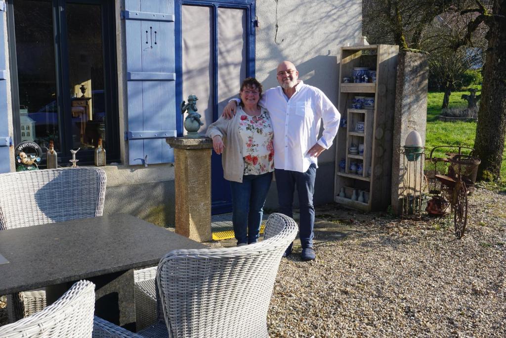 a man and a woman standing in front of a house at Chambre d'hôtes Juste-Confortable in Fleurey-lès-Lavoncourt