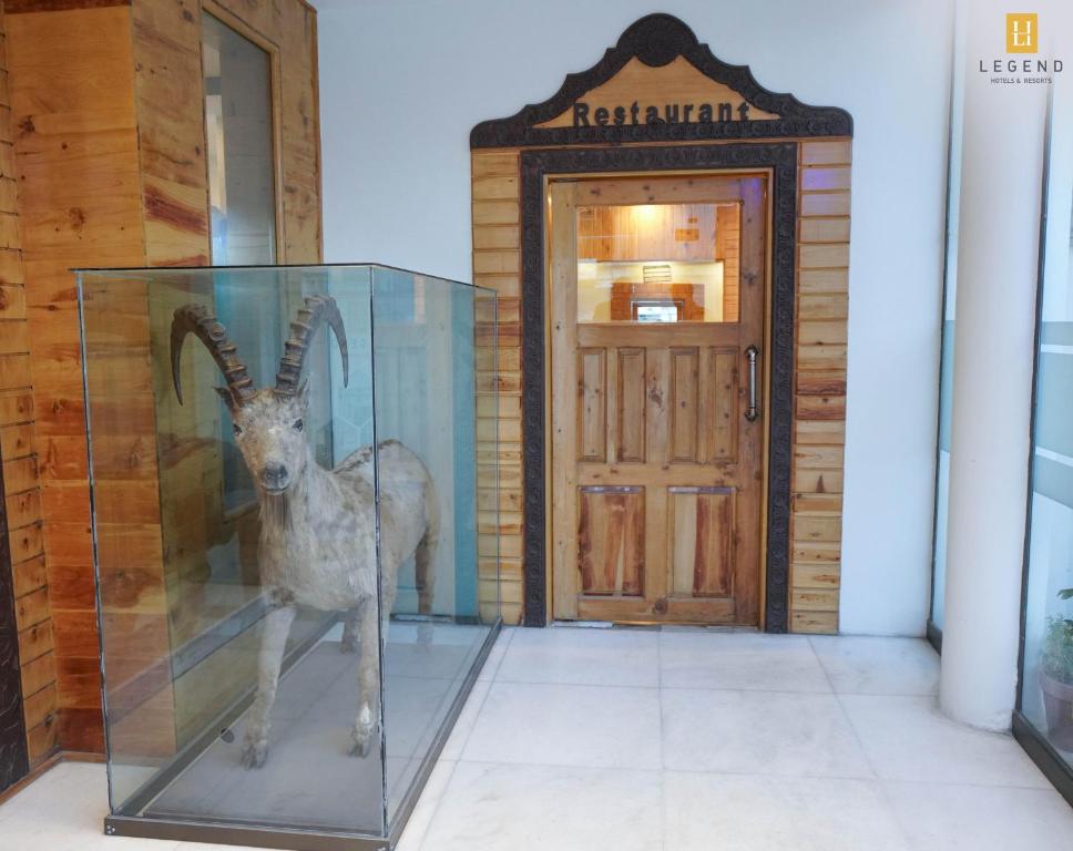a statue of a deer in a glass case next to a door at Legend Hotel Skardu in Skardu