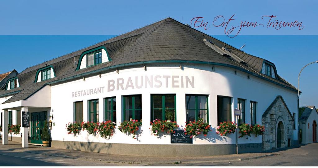 ein Gebäude mit Blumen in den Fenstern auf einer Straße in der Unterkunft Hotel & Restaurant Braunstein - Pauli´s Stuben in Purbach am Neusiedlersee