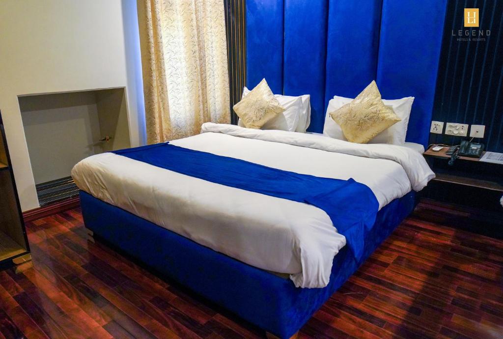 a large bed in a room with a blue wall at Legend Hotel Skardu in Skardu