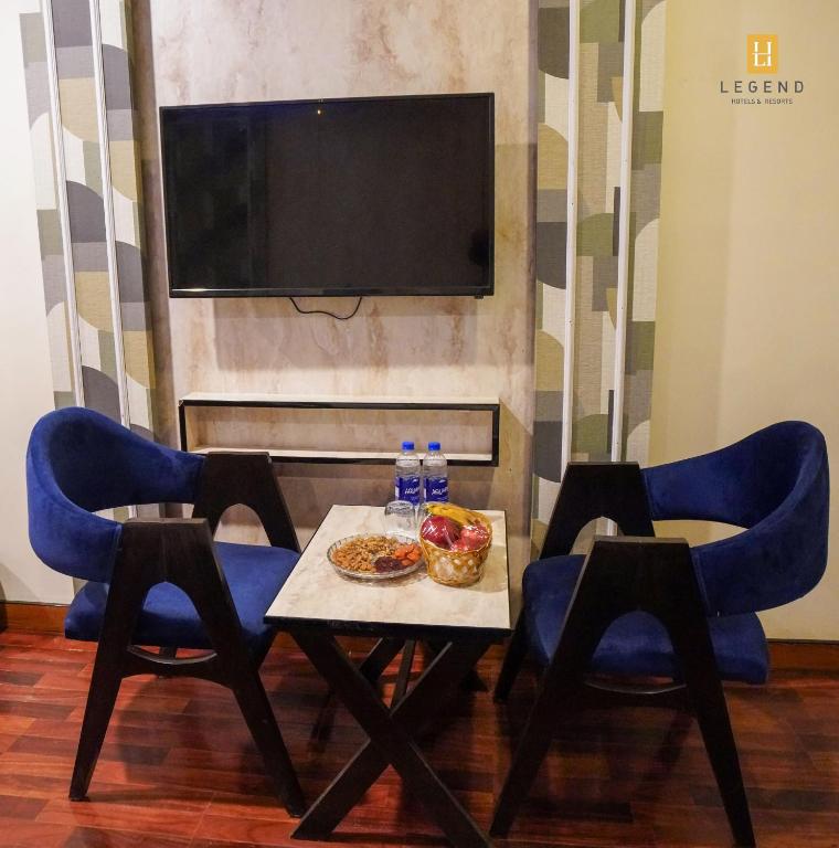 a table with food and two chairs and a television at Legend Hotel Skardu in Skardu