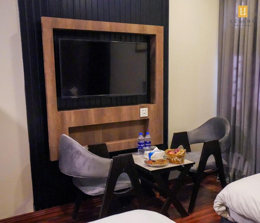 a room with a table and chairs and a tv at Legend Hotel Skardu in Skardu