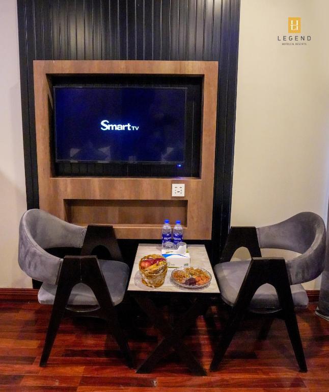 a table with two chairs and a tv in a room at Legend Hotel Skardu in Skardu