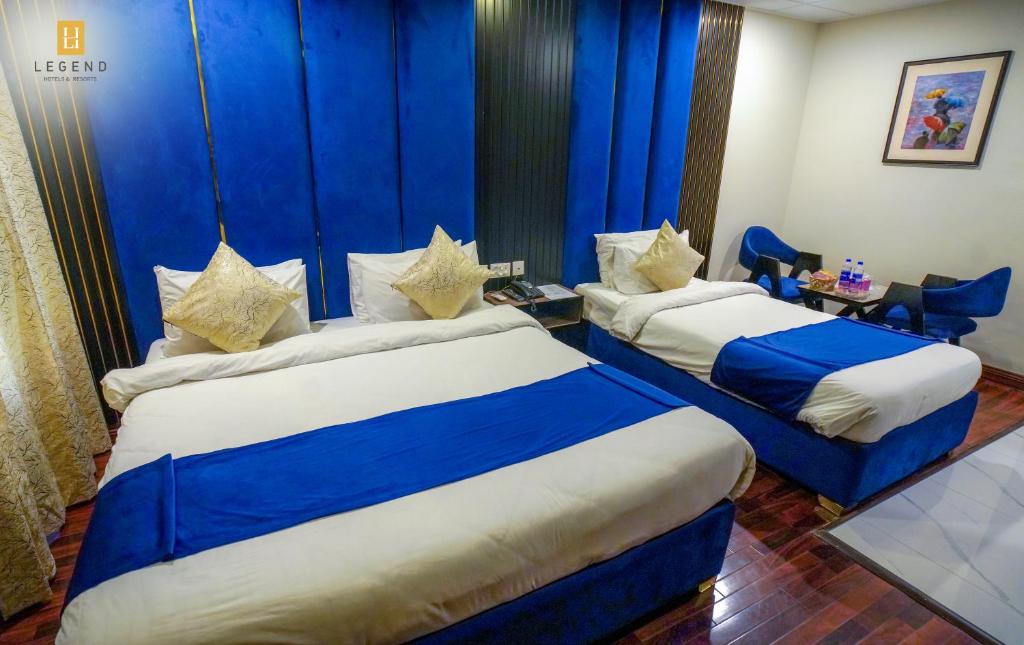 two beds in a hotel room with blue curtains at Legend Hotel Skardu in Skardu