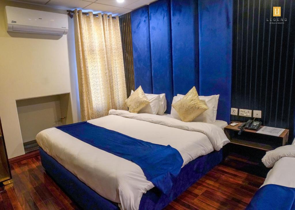 a bedroom with two beds and a blue wall at Legend Hotel Skardu in Skardu