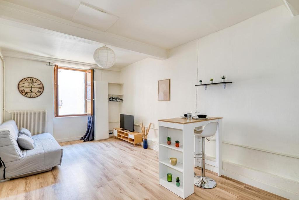 un salon avec un canapé et une horloge au mur dans l'établissement Studio cosy - Plein coeur de Neuville, à Neuville-sur-Saône