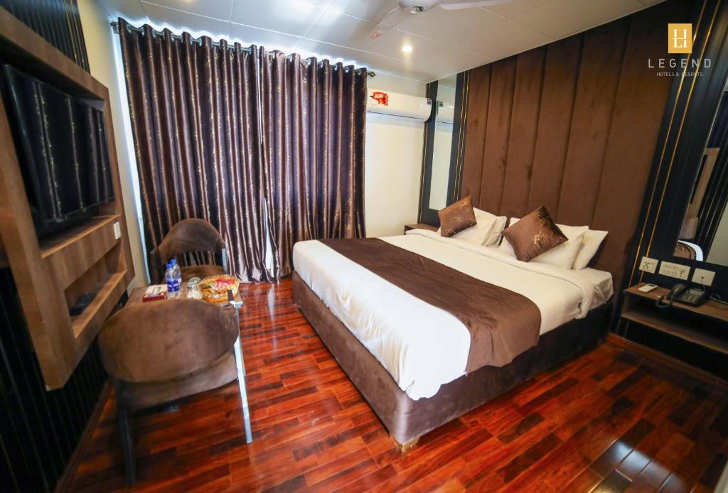 a bedroom with a bed and a chair and a table at Legend Hotel Skardu in Skardu