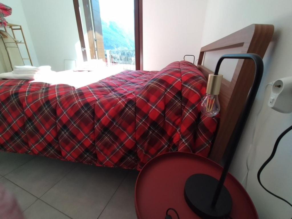 a bedroom with a bed with a red plaid blanket at Adamello Peak ONE Apartment in Temù
