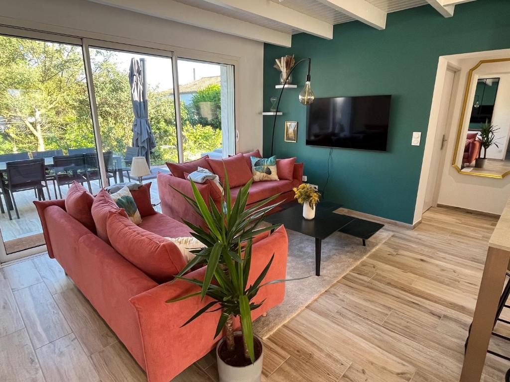 a living room with a red couch and a television at Maison 4 chambres & jardin à Chéray in Saint-Georges-dʼOléron