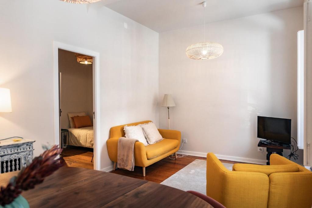 a living room with a yellow chair and a television at SUNNY PATIO Apartment in Lisbon