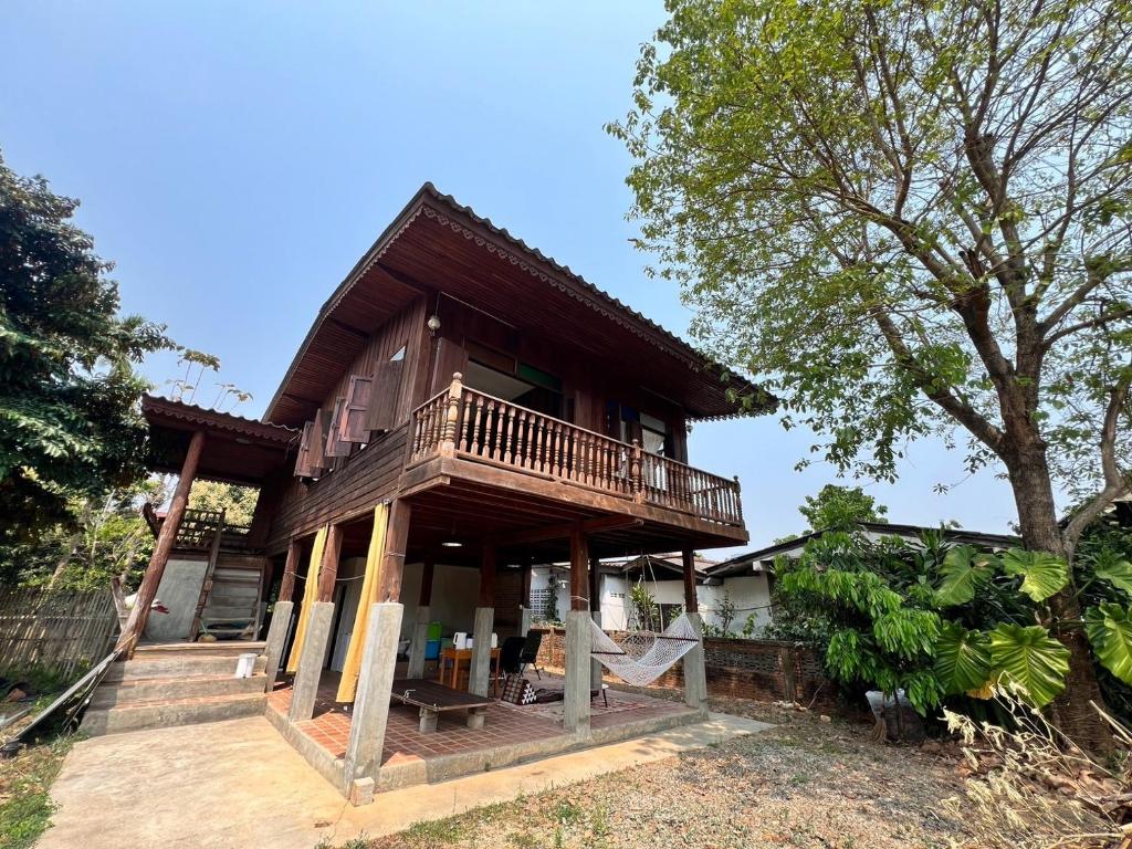 a house with a balcony and a tree at The Say Ba Homestay at Mae Chaem เด๊อะเซ่บะ โฮมสเตย์ แม่แจ่ม in Mae Chaem