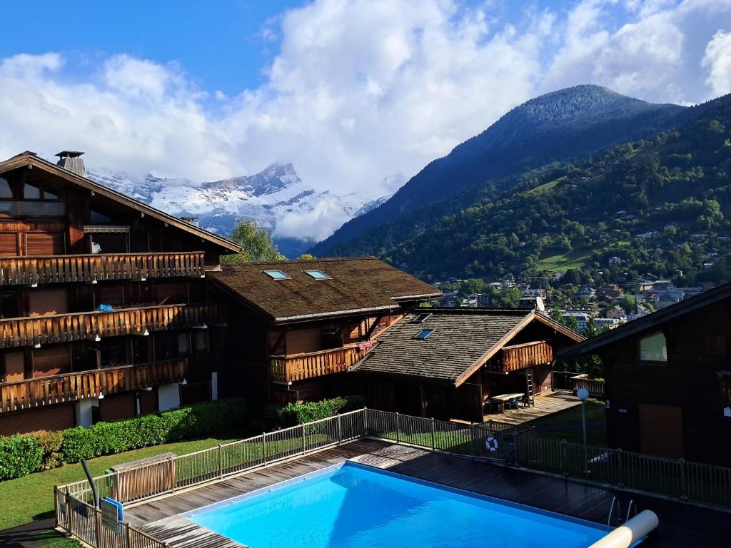 un complexe avec une piscine et des montagnes en arrière-plan dans l'établissement Au coeur des Alpes, à Saint-Gervais-les-Bains