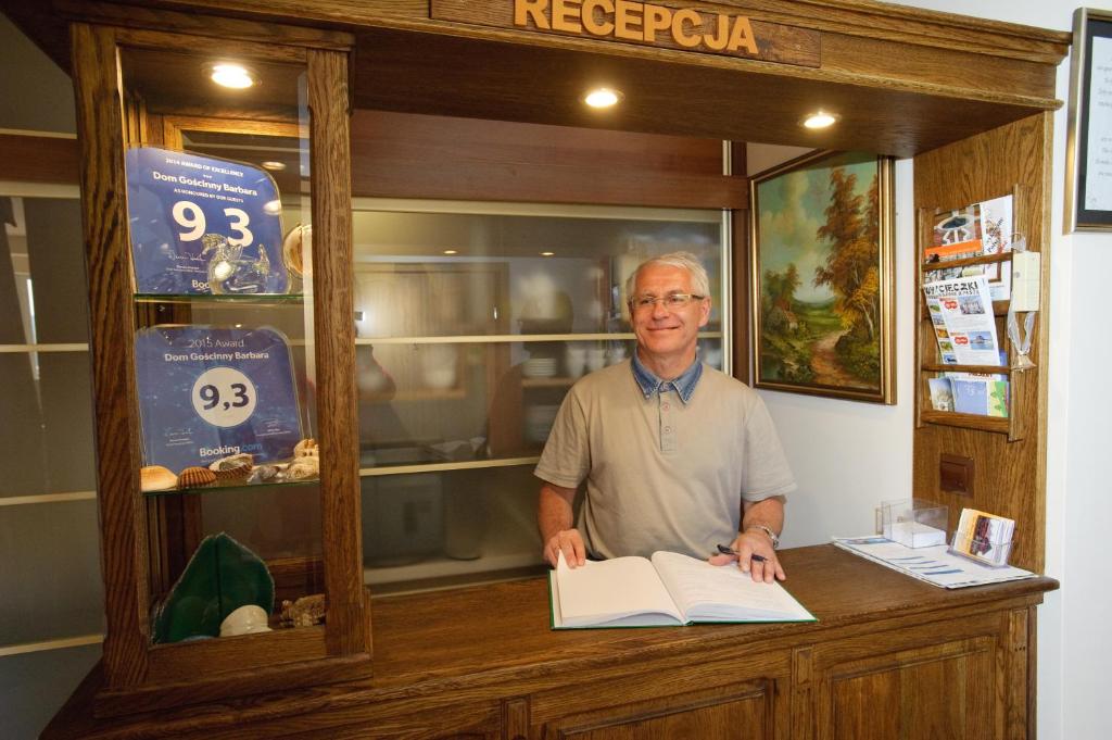 a man standing at a counter with a book at Dom Gościnny Barbara in Polańczyk