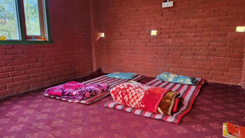 3 Betten in einem Zimmer mit Ziegelwand in der Unterkunft MJ cafe and homestay in Jāmb