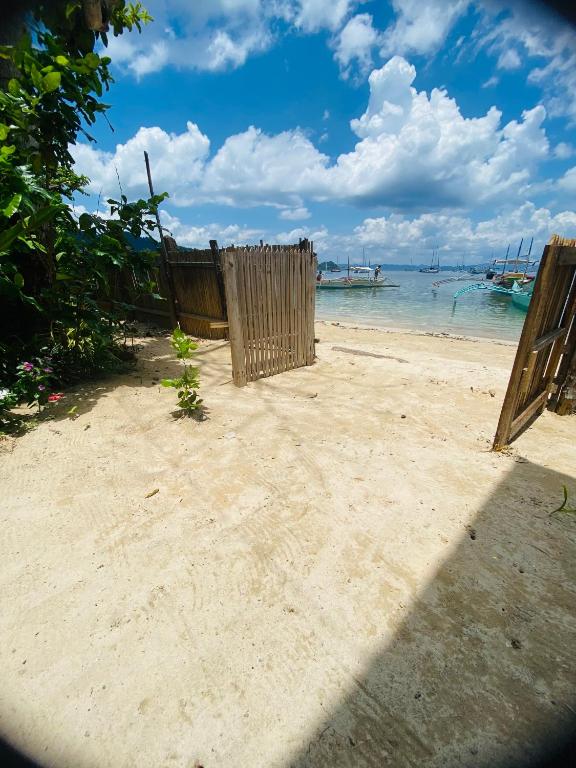 a wooden fence on a beach with the water at Apoheo Beach Cabin Free Use Motrbike Drng Stay in El Nido