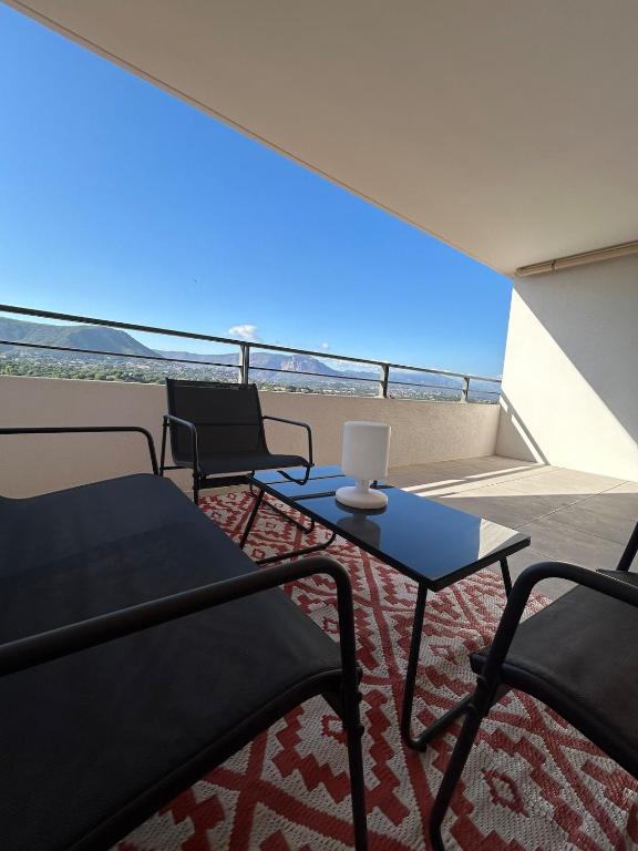 - un balcon avec deux chaises et une table avec un ordinateur portable dans l'établissement Cœur Ajaccio calme plage nature, à Ajaccio