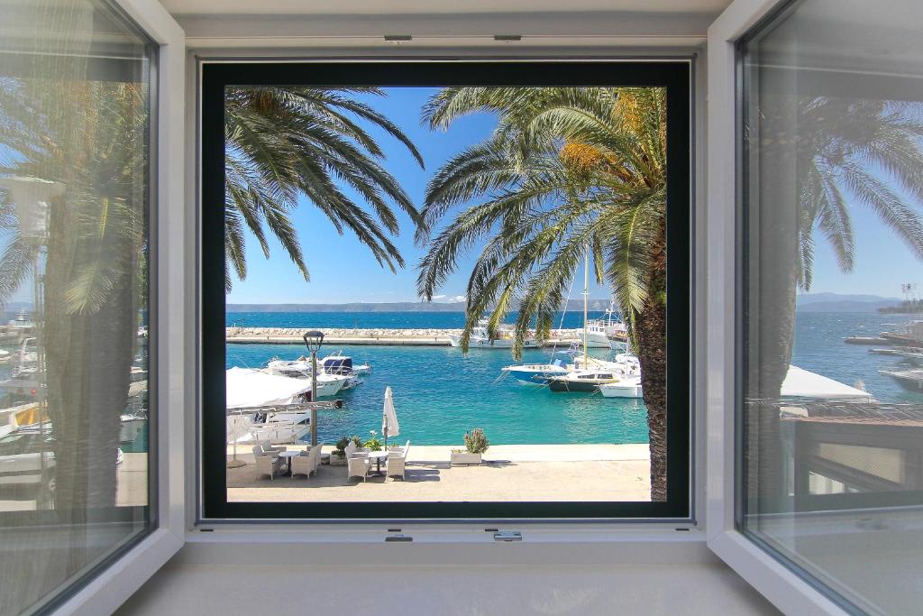a window with a view of a marina with boats at Apartments Nikolina in Podgora