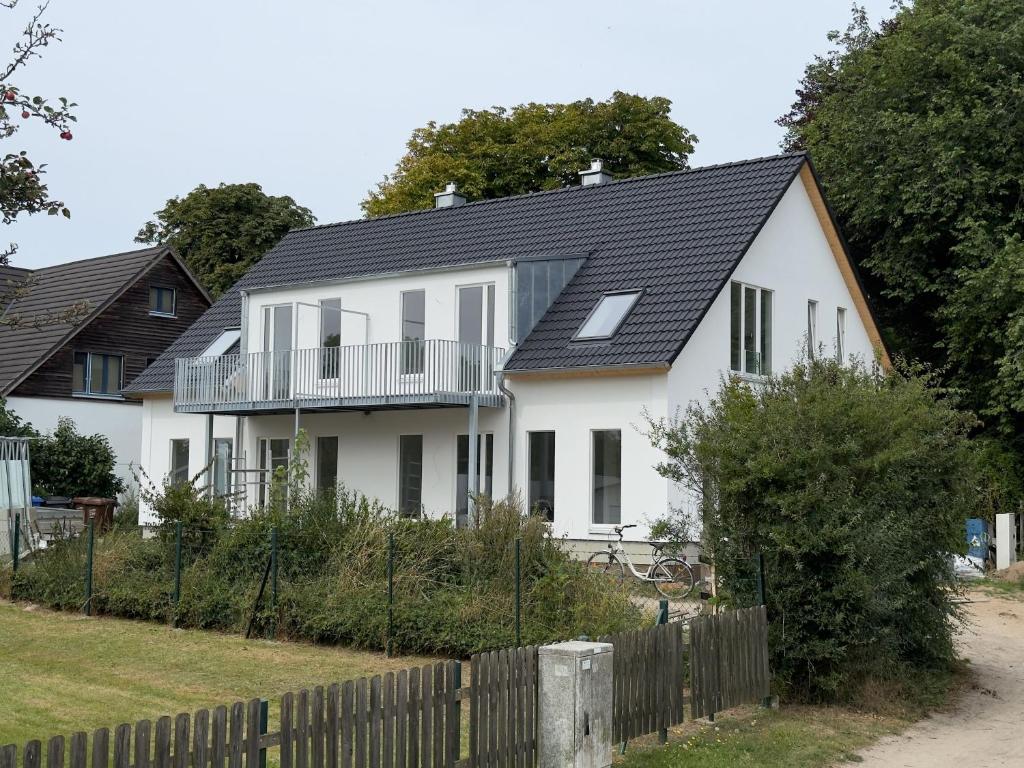 a white house with a black roof at FeWo Clara - Ferienhaus Hiddensee in Kloster