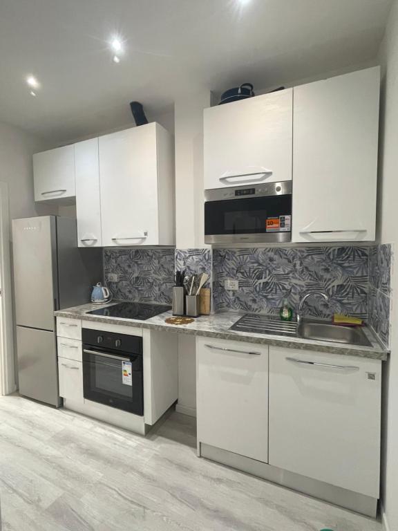 a kitchen with white cabinets and a stove top oven at Muzien B&B in Imola