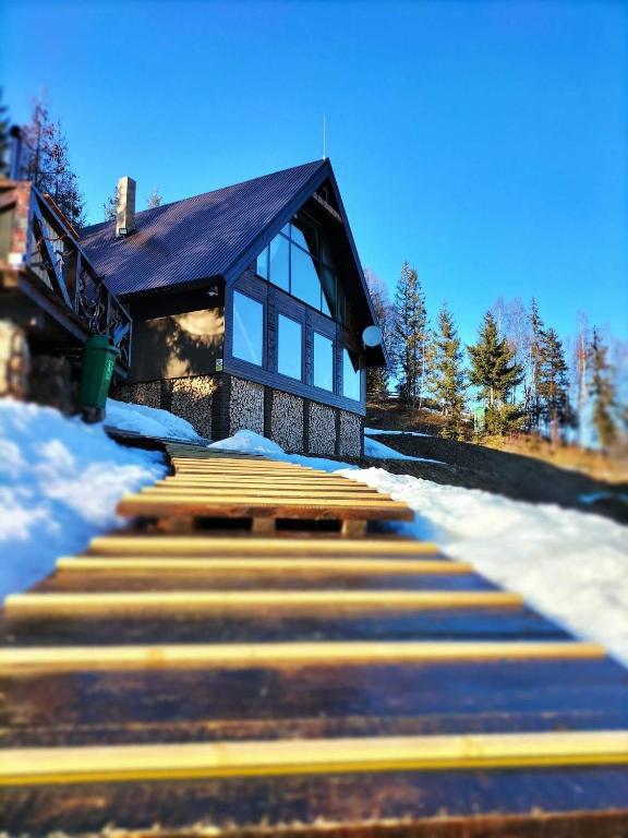 a house with a set of stairs in the snow at Montesse Chalet- La noi la munte in Arada