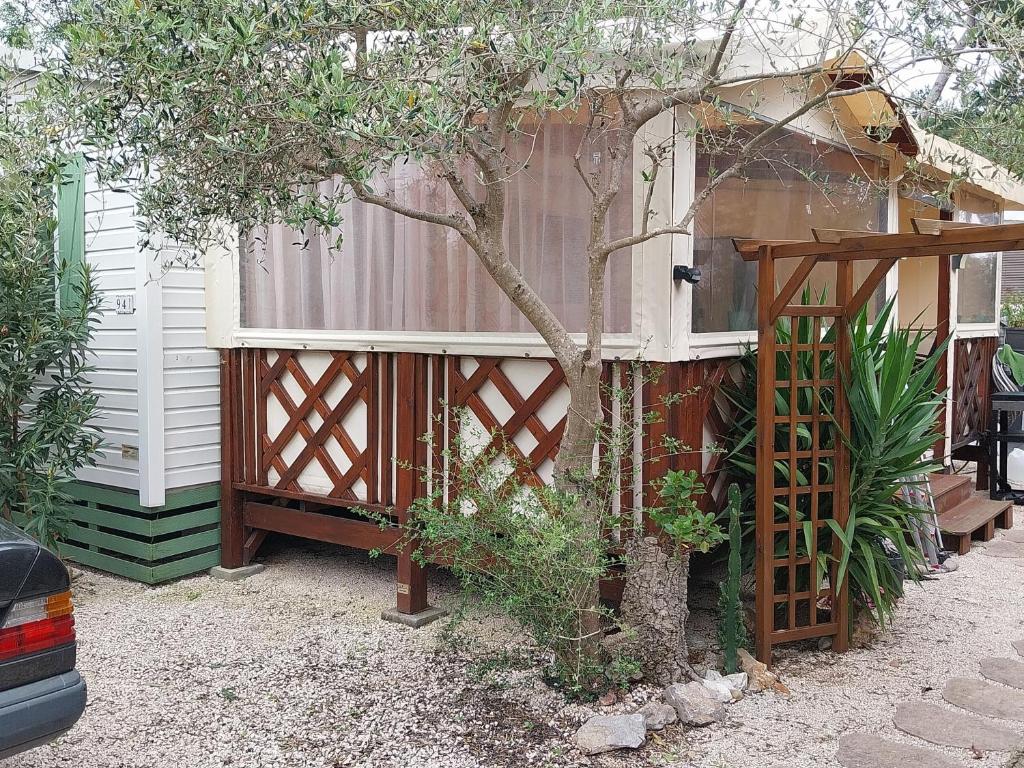 une petite maison avec un arbre et une clôture dans l'établissement MOBILE HOME tout confort à 200m de la plage, à Hyères