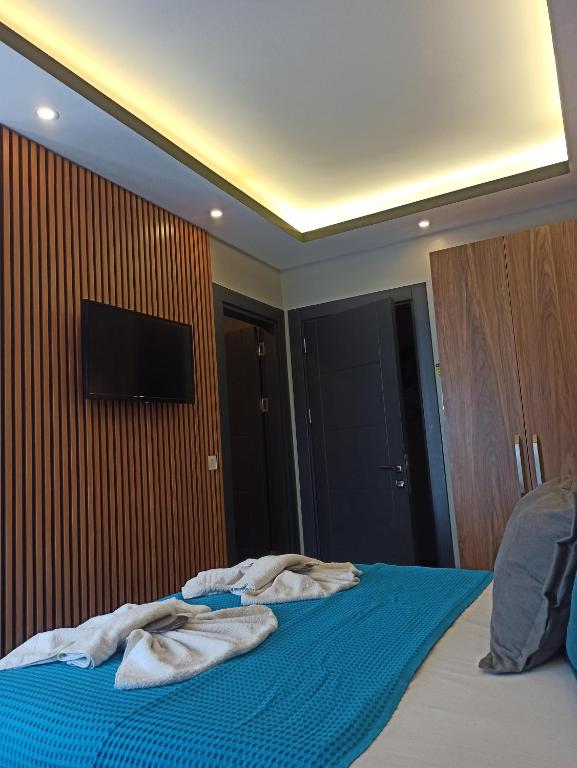 a bedroom with a bed with blue sheets and a flat screen tv at Başar hotel in Erdemli