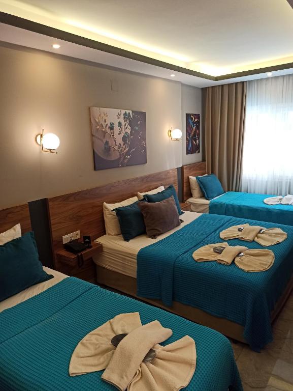 a hotel room with two beds with blue sheets at Başar hotel in Erdemli