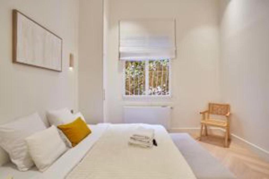 une chambre blanche avec un lit blanc et une fenêtre dans l'établissement Sumptuous apartment with garden Arc de Triomphe, à Paris