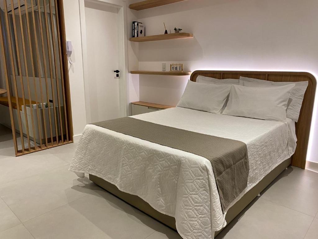 una camera da letto con un letto grande con lenzuola e cuscini bianchi di LOFT Ed Carbono a Blumenau