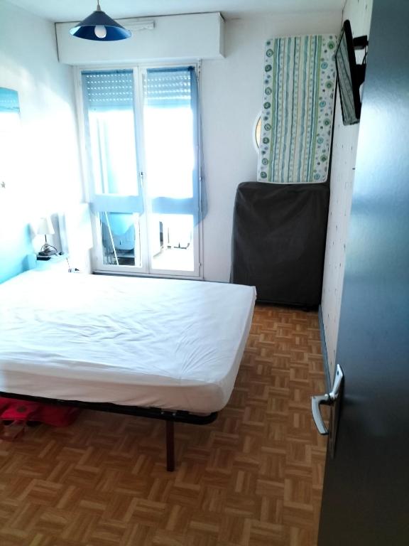 une chambre avec un lit blanc et une fenêtre dans l'établissement Dalhias, à Saint-Hilaire-de-Riez