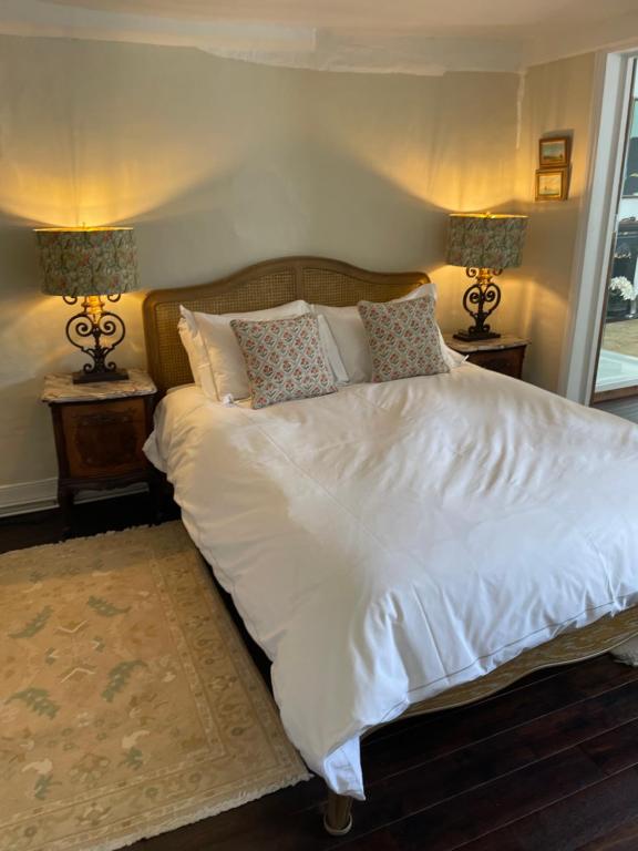 a bedroom with a large white bed with two lamps at Blythe Cottage in Long Melford