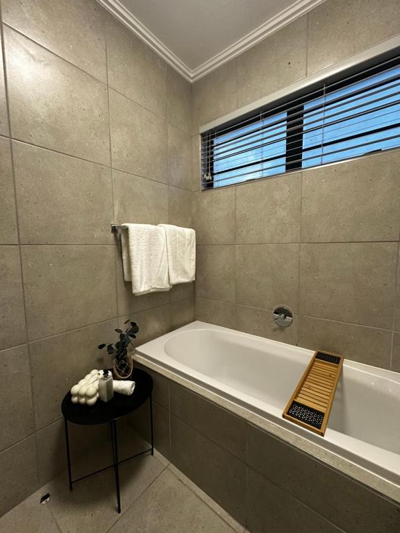 a bathroom with a bath tub and a window at Waterfall Luxury Apartment in Midrand