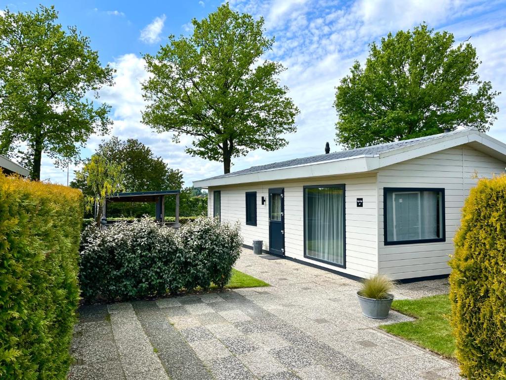 a small white house with trees and bushes at Ruimte, privacy en comfort op de Veluwe, inclusief 2 fietsen & linnengoed in Nunspeet