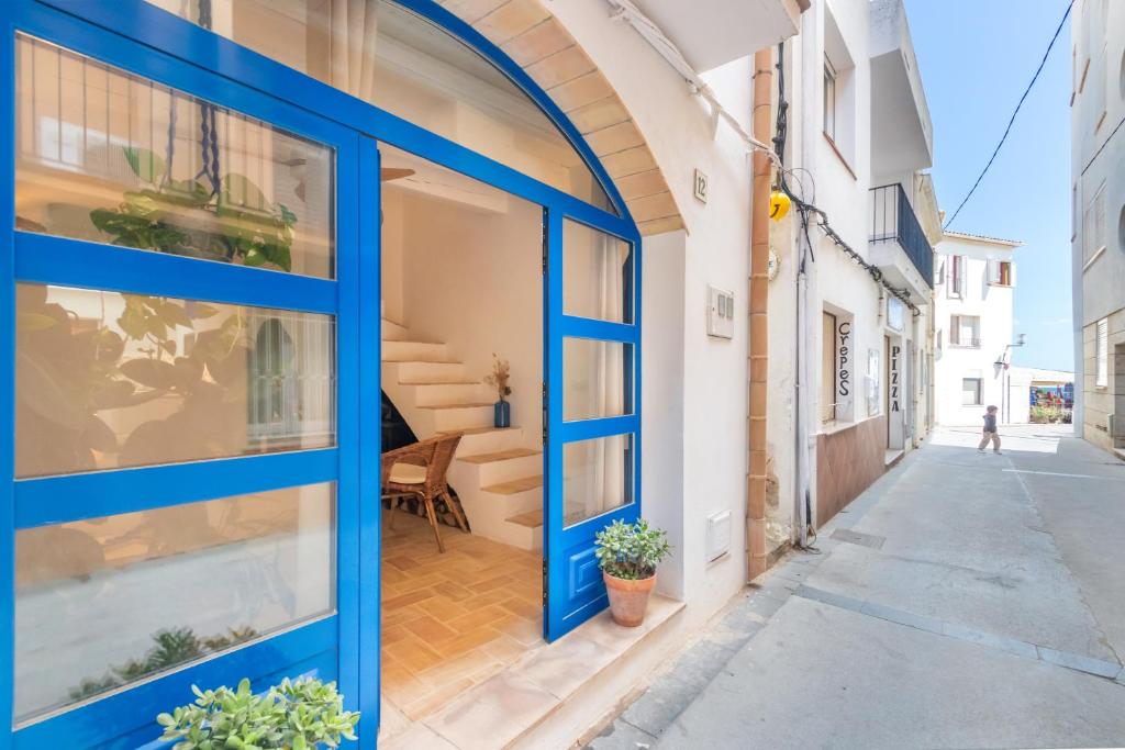 ein Gebäude mit blauen Türen an einer Straße in der Unterkunft Casa con encanto a pie de playa in Tamariu