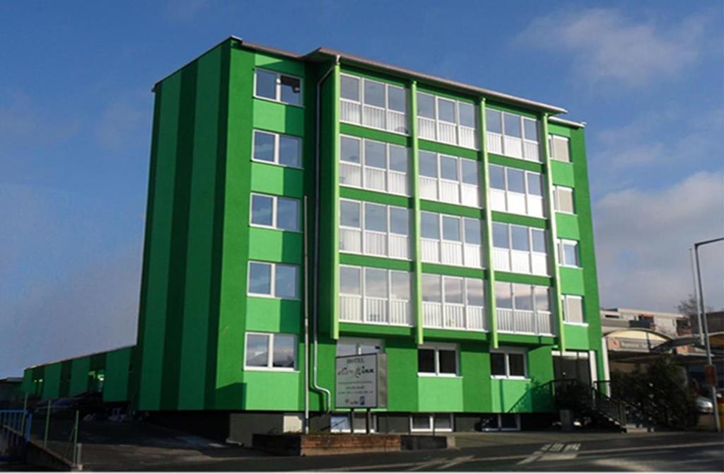 a green building with white windows in a parking lot at Hotel Olive Inn in Aschaffenburg