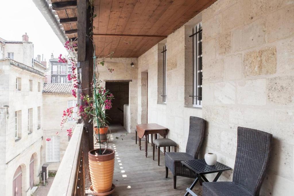 un balcon avec des chaises et une table sur un immeuble dans l'établissement Magnifique Appartement avec Terrasse - Centre Historique, à Bordeaux