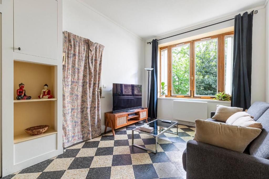 un salon avec un canapé et une télévision dans l'établissement Charmant studio Père Lachaise, à Paris